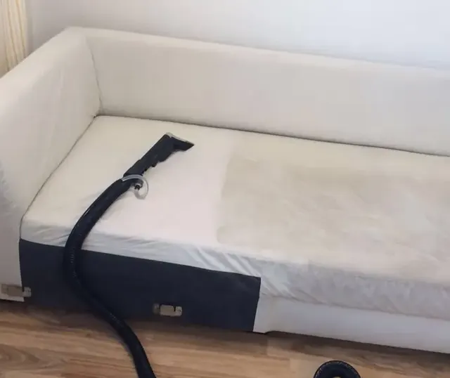 Biela sedačka s tepovacou hubicou, na poťahu je vidieť už vyčistený pruh